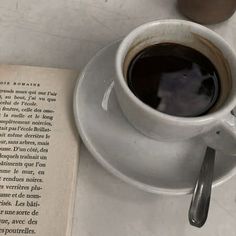 a cup of coffee sitting on top of a saucer next to an open book