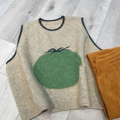 a sweater and pants are sitting on the floor next to each other, one with an apple drawn on it