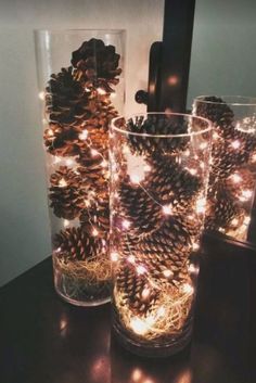 two glasses filled with pine cones sitting on top of a table next to each other