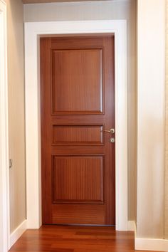 an empty room with a wooden door and hard wood flooring