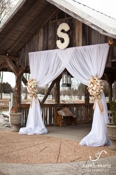 an outdoor wedding venue with white drapes and floral arrangements on the front door area