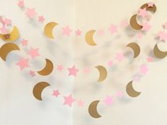 paper stars and crescents are hanging on the wall with pink and gold confetti