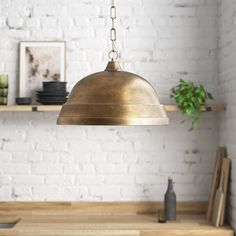 an industrial style pendant light hanging from a wooden table in front of a white brick wall