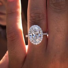 a woman's hand with a diamond ring on top of her finger and an engagement band