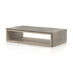 a concrete coffee table sitting on top of a white floor next to a wooden shelf