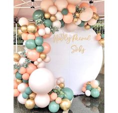 a large balloon arch is decorated with pastel balloons and greenery