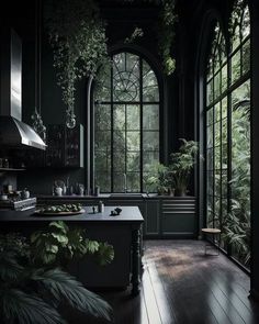 a kitchen with dark green walls and wooden flooring, surrounded by greenery is lit by an arched window