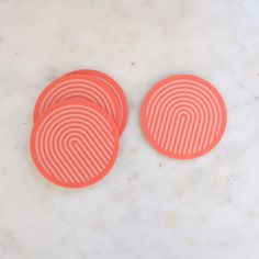 three orange frisbees sitting on top of a white marble counter next to each other