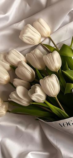 a bouquet of white tulips laying on top of a bed