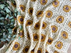 a crocheted blanket with sunflowers on it next to a potted plant