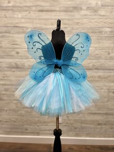 "Fuzzy Duckling Design dresses ~ handcrafted for the little princess in your life. This adorable tutu set includes the tutu skirt, matching ribbon crown and coordinating fairy wings. * The full skirt sparkles and shines with three layers of high quality tulle in matte, shimmer, and glitter finishes. * Tulle is hand-tied onto a wide crocheted band, with an elastic band woven through the material for ease in taking it on and off. * A wide satin ribbon bow is tied to the front of the skirt for an e Blue Fitted Tutu Dress For Costume, Fitted Blue Tutu Dress For Dress-up, Blue Fitted Costume For Dress-up, Cute Blue Sets For Birthday, Cute Blue Party Sets, Cute Blue Tutu Dress For Costume Party, Whimsical Blue Fitted Tutu Dress, Blue Princess Costume For Party, Blue Whimsical Fitted Tutu Dress