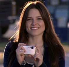 a woman holding a camera and smiling at the camera