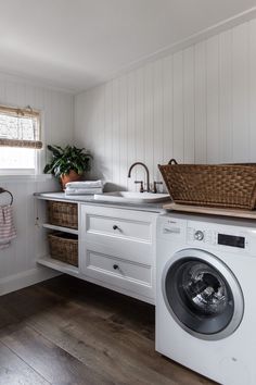 a washer and dryer in a small room with white walls, wood floors and wooden flooring