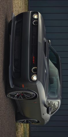 the front end of a grey truck parked on top of a parking lot next to a building