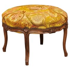 an upholstered foot stool with yellow and orange fabric on the top, sitting in front of a white background