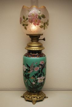 a green vase sitting on top of a table next to a light that is turned on