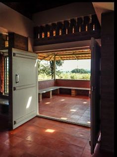 an open door leading into a room with red tile flooring and wooden ceiling beams