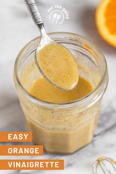 an orange sauce in a glass jar with a spoon full of it and the words easy orange vinaigrete