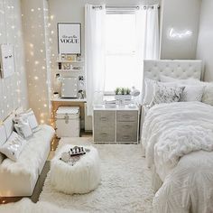 a bedroom decorated in white and gray with lights on the walls, bedding, rugs and pillows