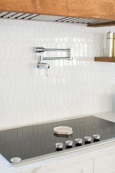 a stove top oven sitting inside of a kitchen next to a wooden shelf above it