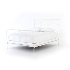 a white metal bed with two pillows on it