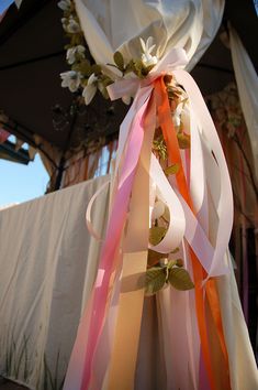 an umbrella with ribbons tied to it and flowers on top, in front of a building