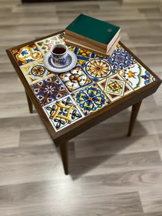 a table with a coffee cup and books on it, sitting on top of a hard wood floor