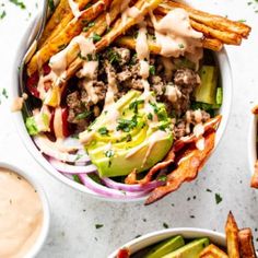 two bowls filled with different types of food and some dipping sauces on the side