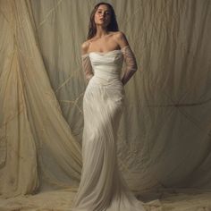 a woman in a white dress is posing for a photo with her hands on her hips