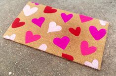 a brown bag with pink and red hearts painted on it sitting on the ground next to a sidewalk