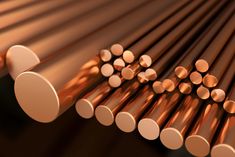 several different types of copper bars are arranged in the shape of an arrow on a dark background