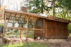 a chicken coop in front of a wooden building