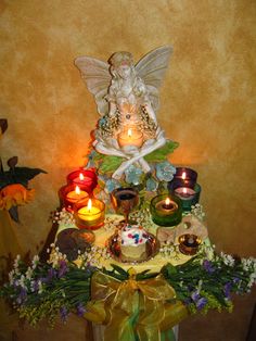 a table topped with candles and a fairy figurine