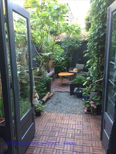 an open door leading to a small patio with potted plants on either side and a table in the middle