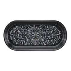 a black tray with a skull and leaves design on the bottom, in front of a white background