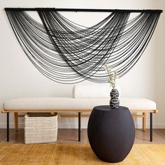 a black vase sitting on top of a wooden floor next to a white couch and table