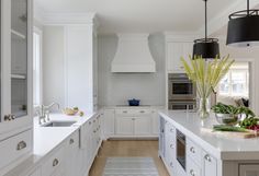 a large kitchen with white cabinets and counter tops, along with an area rug on the floor