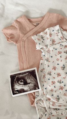 two baby onesuits are laying next to an old photo