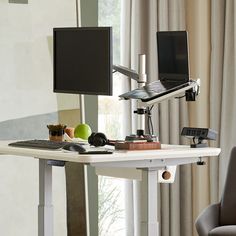 a computer desk with a monitor, keyboard and mouse sitting on top of it next to a window