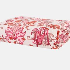 a pink and red floral print blanket on top of a white bed sheet with an elephant design