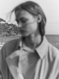 a woman standing in front of the ocean with her eyes closed and head tilted to the side