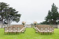 rows of chairs set up in the grass for an outdoor ceremony with flowers and greenery