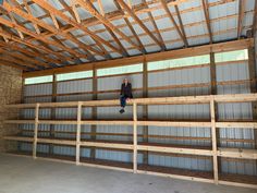 a man standing on top of a wooden floor in a building with metal walls and beams