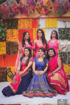 a group of women standing next to each other in front of a colorful wall with flowers