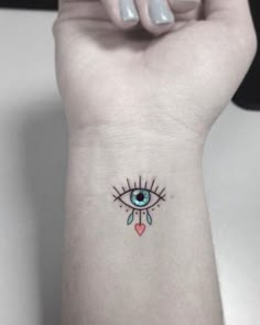 a woman's wrist tattoo with an evil eye and heart in the center on her left arm