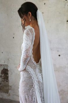 the back of a woman wearing a wedding dress with long sleeves and a veil on her head