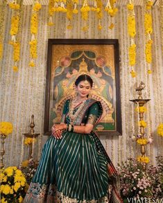 a woman sitting in front of a painting with yellow flowers hanging from it's ceiling