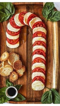 sliced tomatoes, mozzarella and basil on a wooden platter with garlic bread