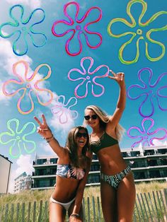 two beautiful young women standing next to each other in front of a flower design kite