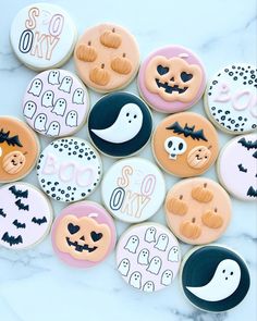 decorated cookies are arranged on a marble surface with black and white decorations in the shape of halloween faces